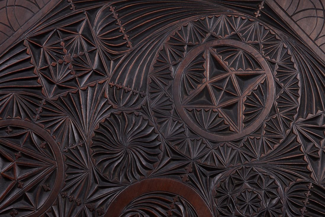 Table top detail  Detail of chip-carving on an occasional table, made by carpenter George Stevenson Liggins (1874 -1907), Melbourne, c1902. 80(h) x 59(w) x 59cm(d).  The outlines of the patterns are incised with chisels, the ground then removed with gouges, leaving the ornament flat and, as far as possible, arranged on one plane, to ensure leaves or flowers do not intersect. Finishes were achieved through stains based on Ammonia or mixtures of bee’s wax, with a variety of recipes created by tradesmen to produce particular results.  Caroline Simpson Library & Research Collection, Photograph © Museums of History NSW. Gift of Frederick and Margaret Liggins. [L2010/41]