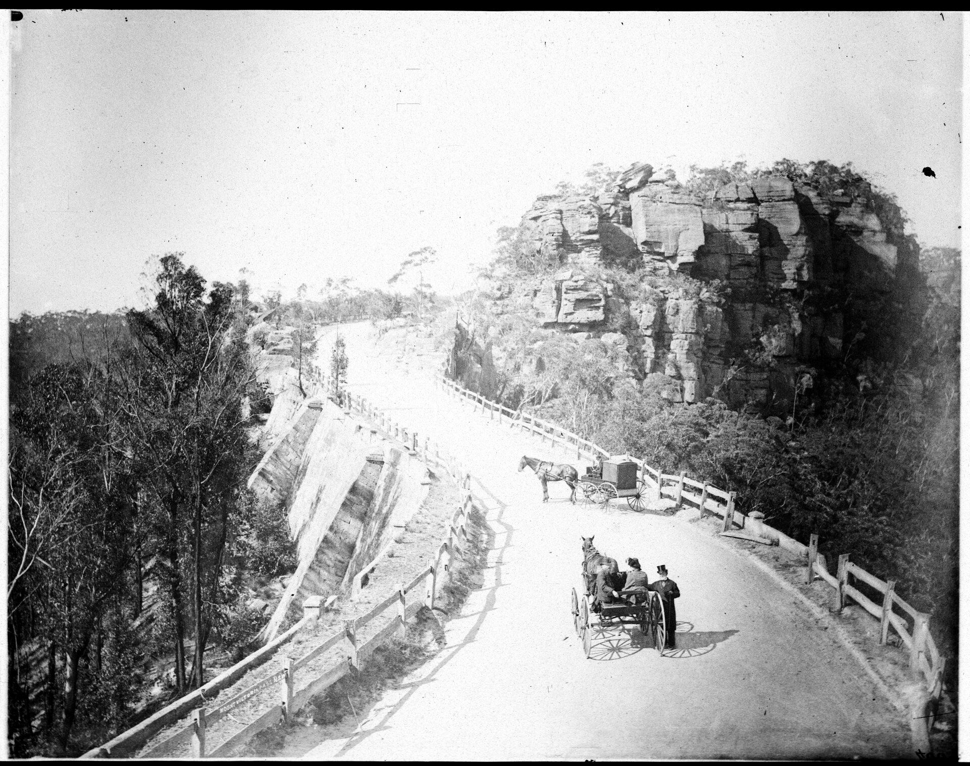 On a steep road towards the peak of a mountain two horses and carts with passengers rest