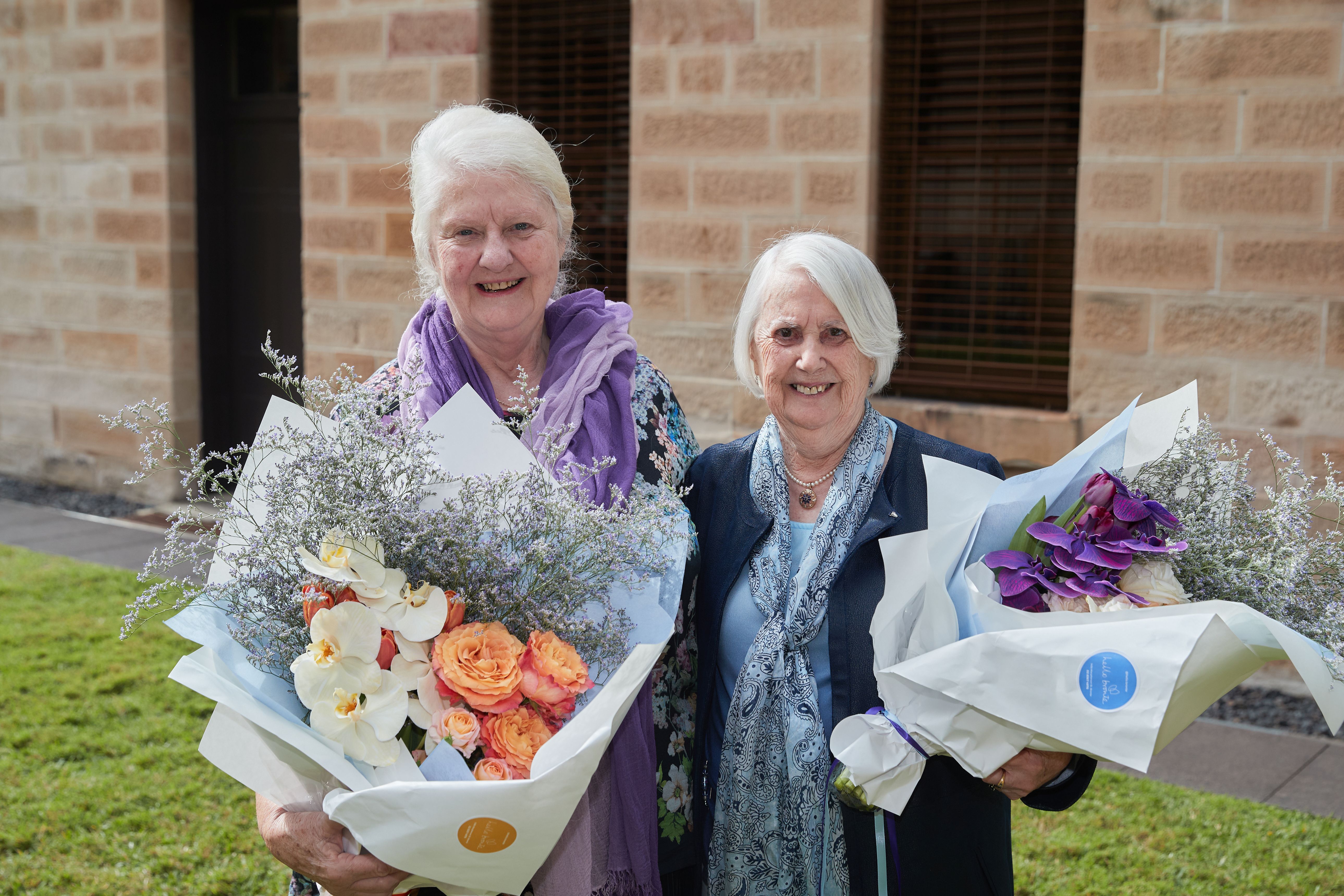 Volunteers Laraine (left) and Elaine (right) each holding a bunch of flowers