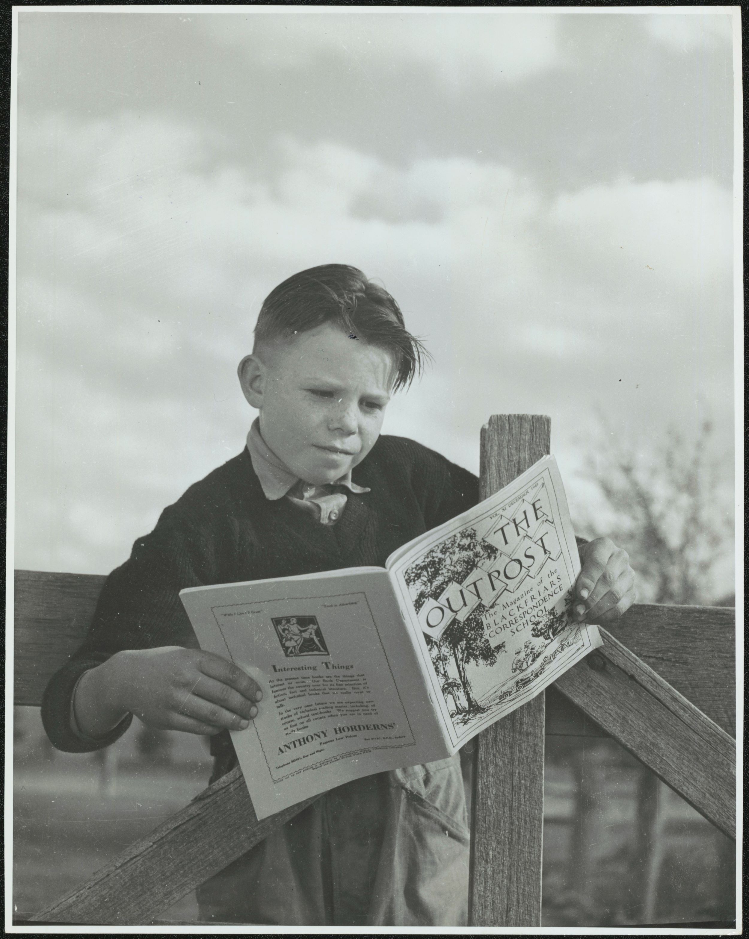 A  boy reads the Correspondence School's magazine The Outpost