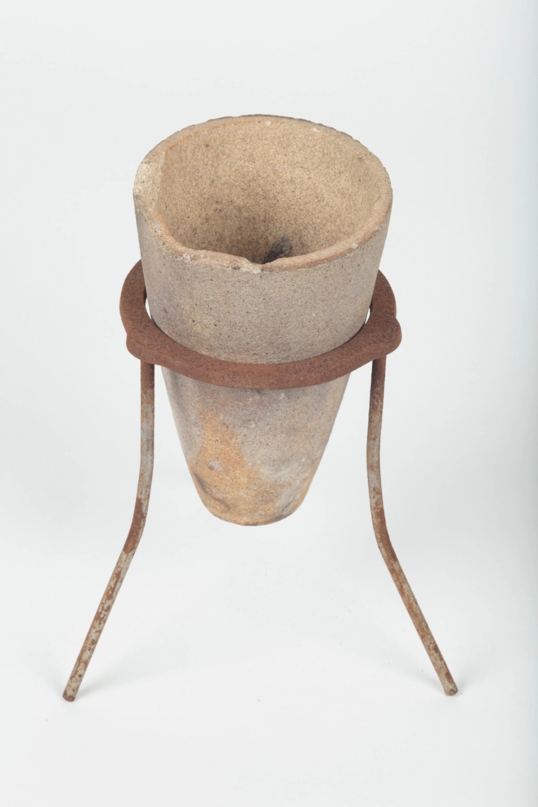 A small deep terracotta pot sits on a tripod