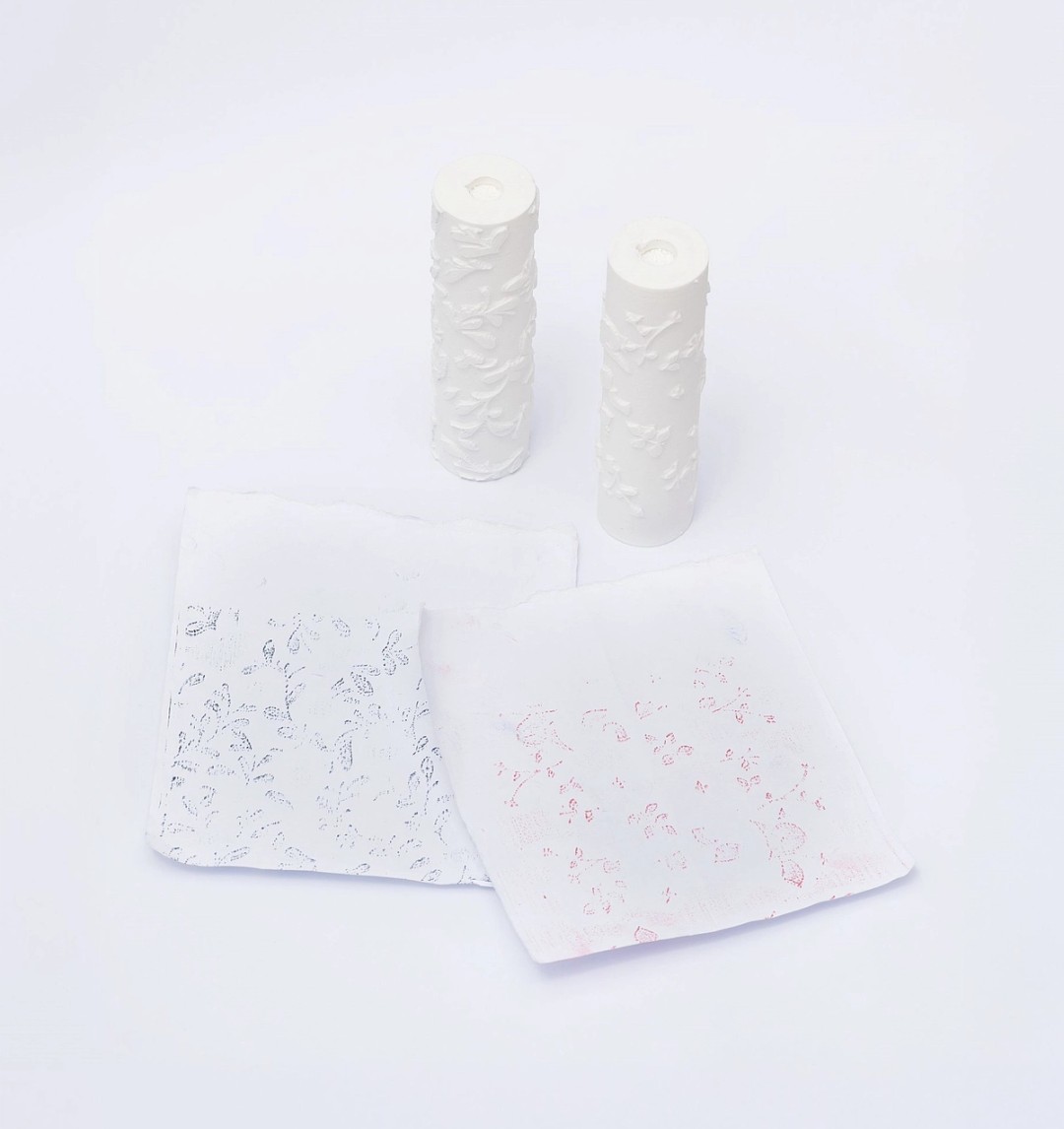 Reduced-size 3D prints of the wallpaper rollers shown with imprints of their designs