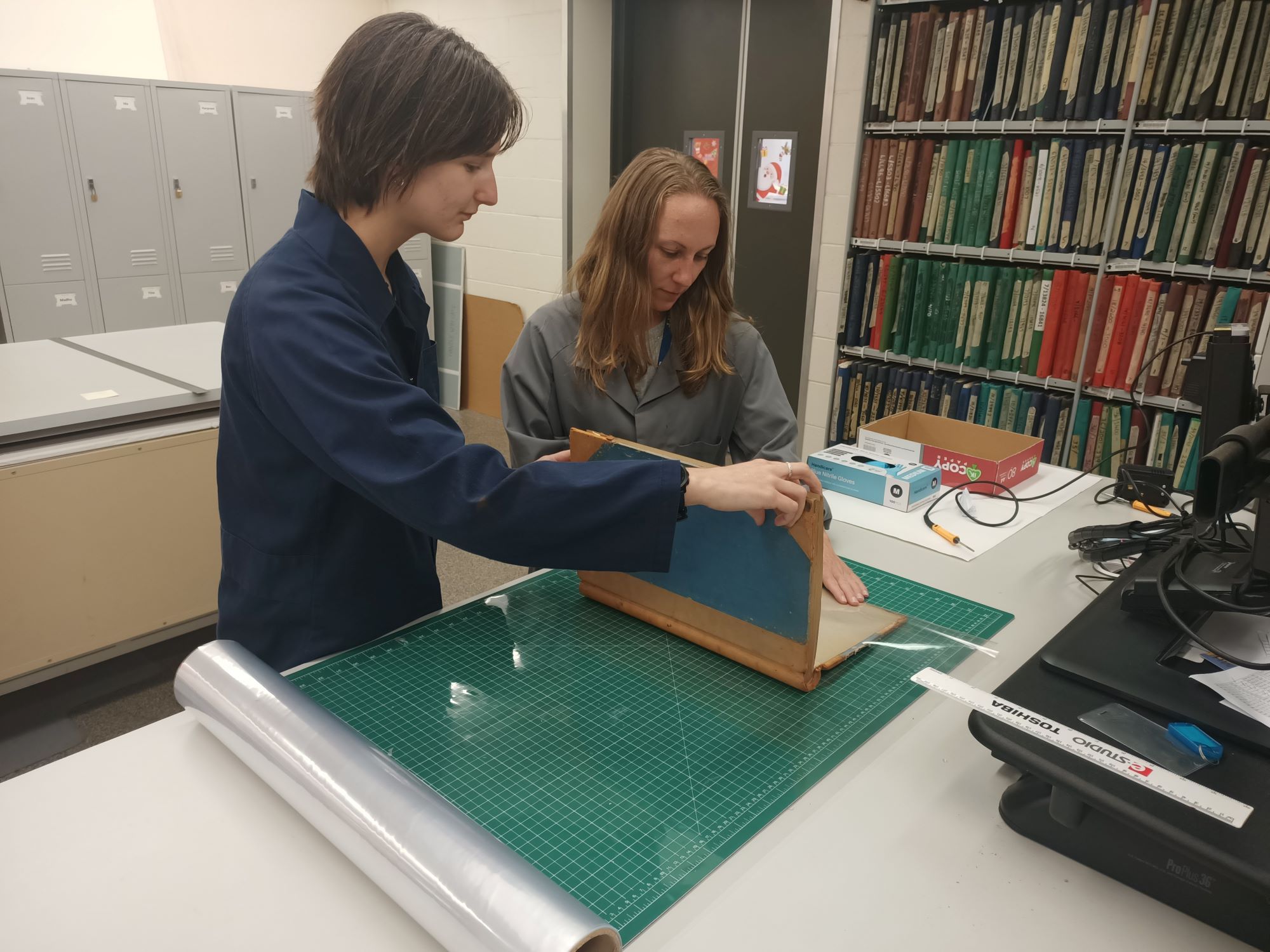 Two people handling a book, processing the accession