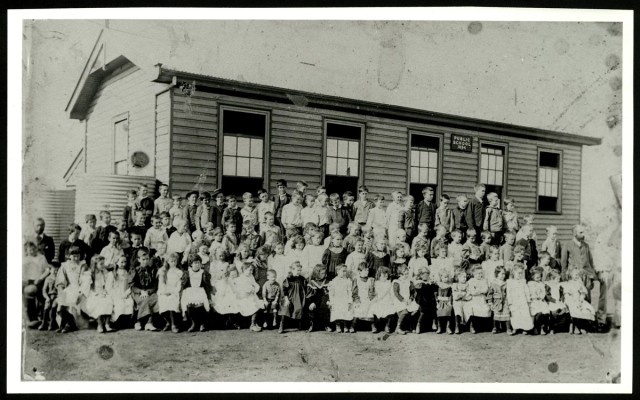 Students pose for photo in front of school building