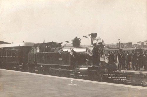 Spectators look at a train decorated in bunting. Written on the photo is: First train leaving new Central Station Sydney 4/8/06