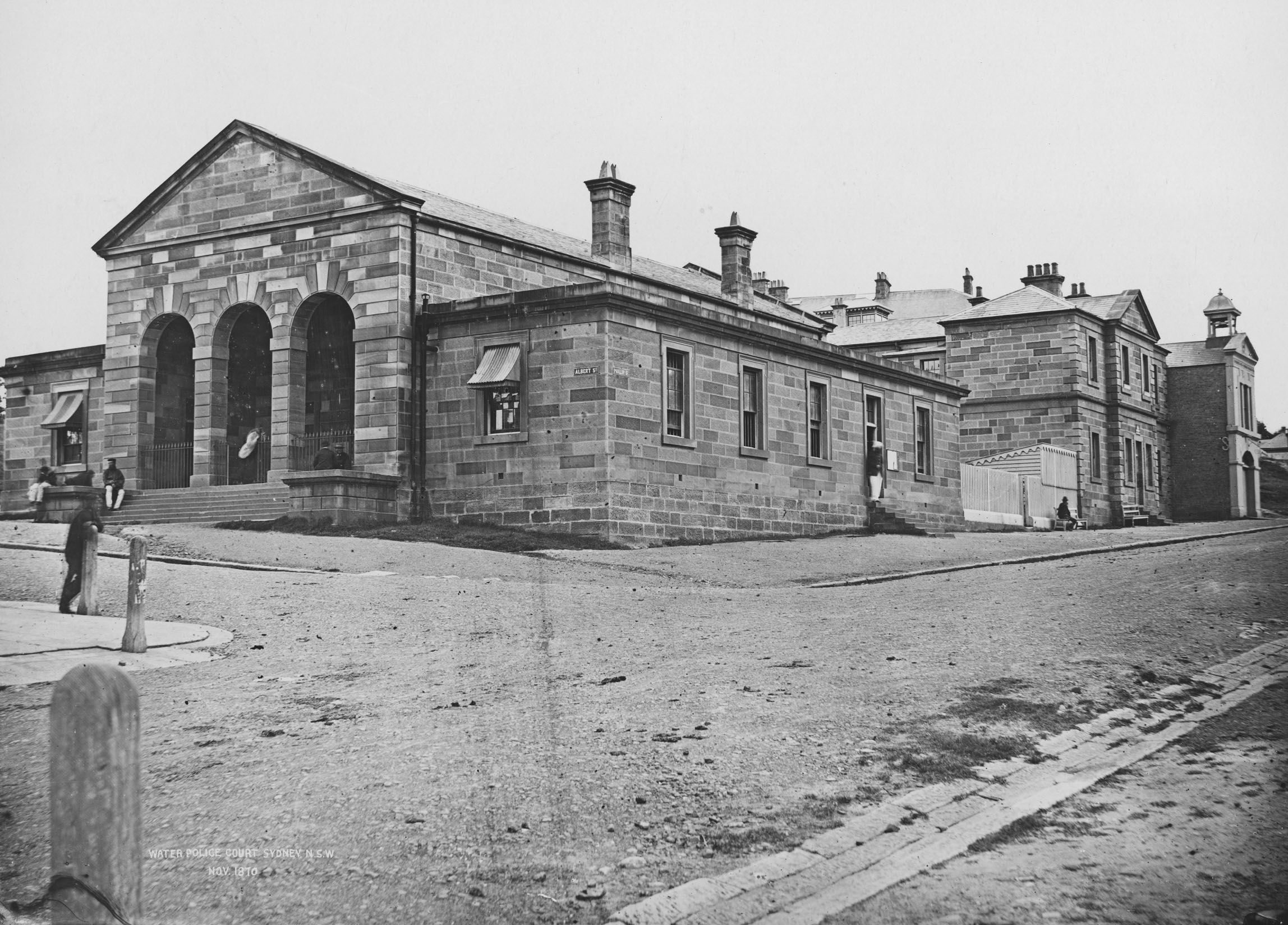 Black and white image of a sandstone building. A man can be seen in the foreground.