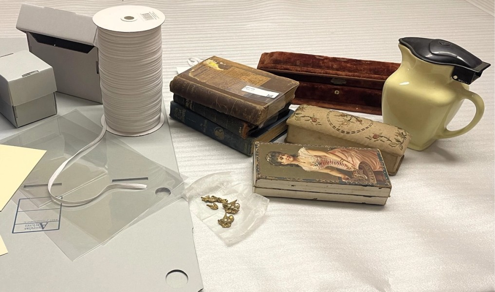 Objects from a collection sit next to archival storage boxes