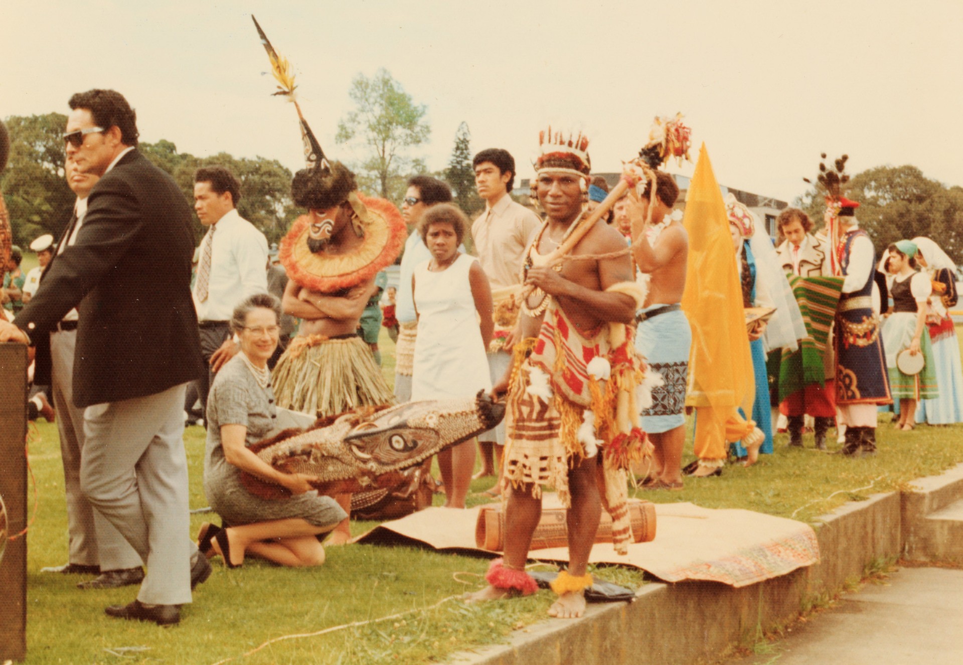 A person crouching and holding the mask, between Papua New Guinea soldiers 