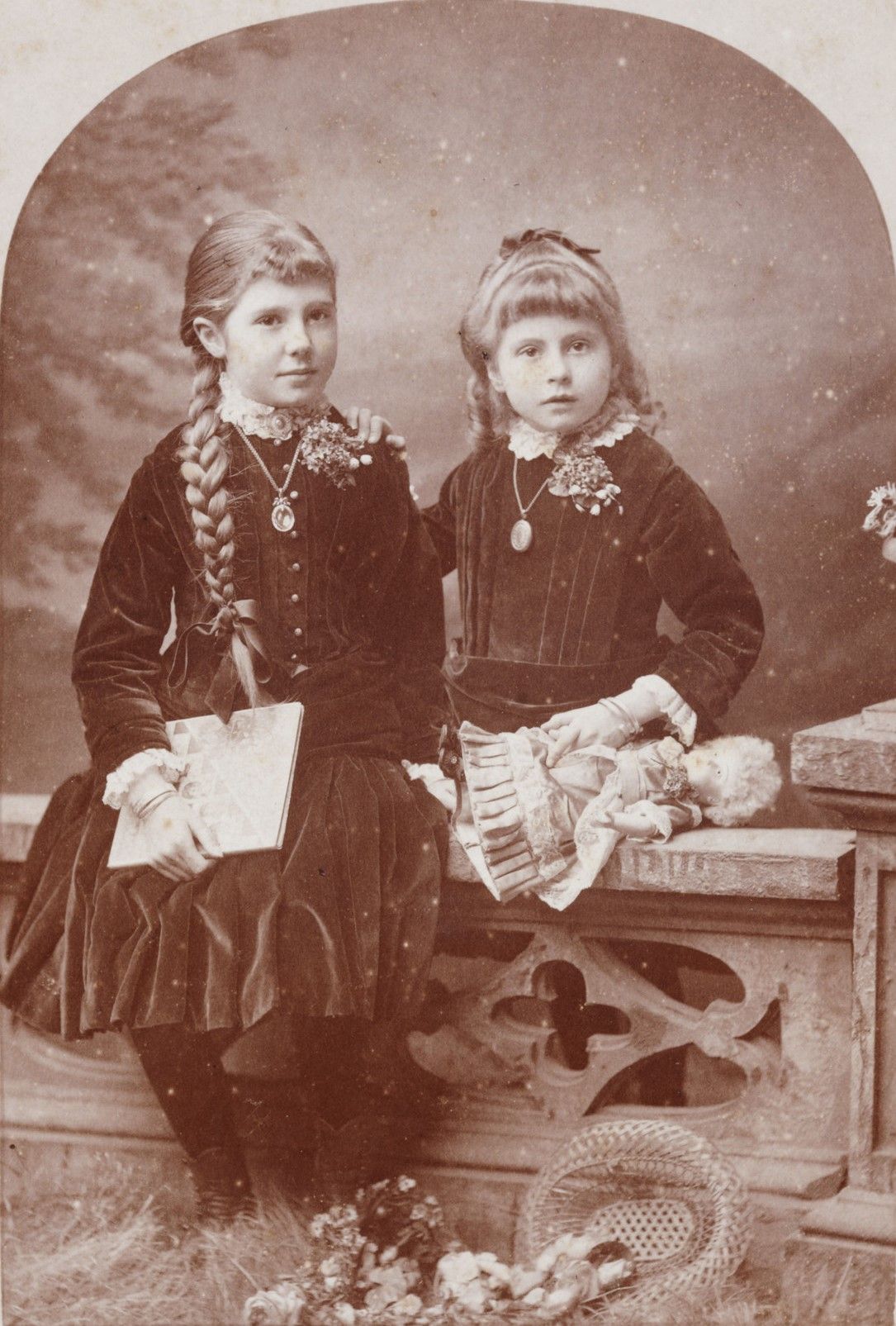 Image of two young girls holding a book and a doll