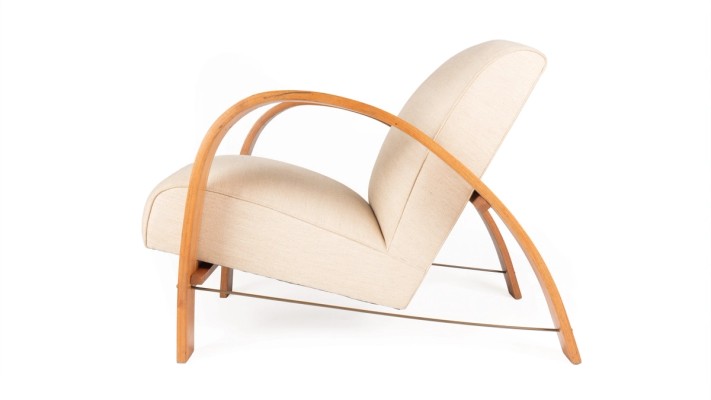 A chair with curved timber arms that bend to become legs with a white abolstered seat.