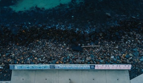 These installations were designed in collaboration with Sydney Water to protect the stormwater plant at the southern end of Fishermans Beach. They appear at the base of Hill 60, a steep hill that was used by the military in World War II as a strategic lookout and munitions site. Traditionally, Aboriginal people used the hill and beach as a campsite. Together, these two works tell of whale migration, fishing, traditional life in this place, and the local Five Islands Dreaming story, as well as the industrialisation of the area. 