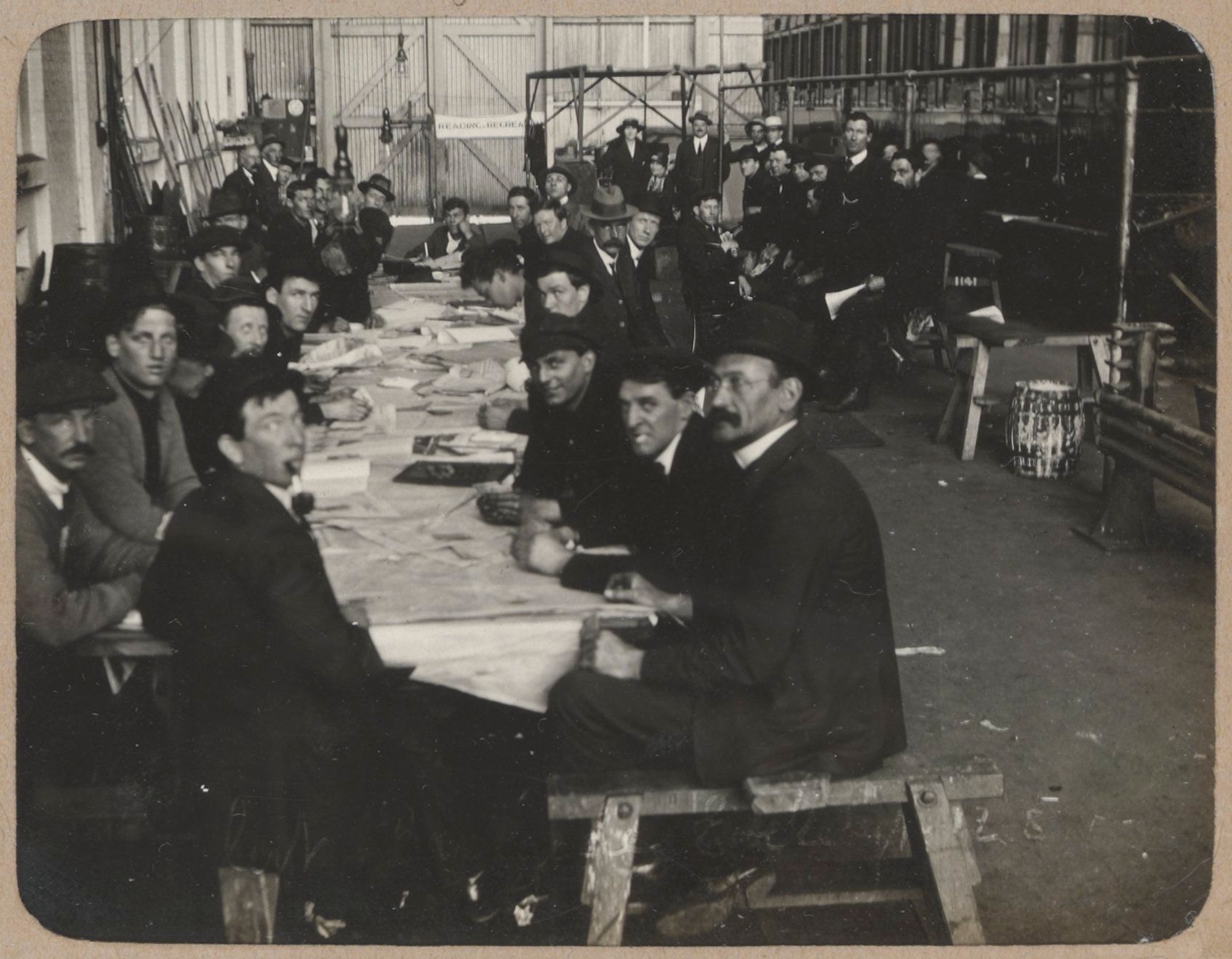 Men sit at long tables reading newspapers