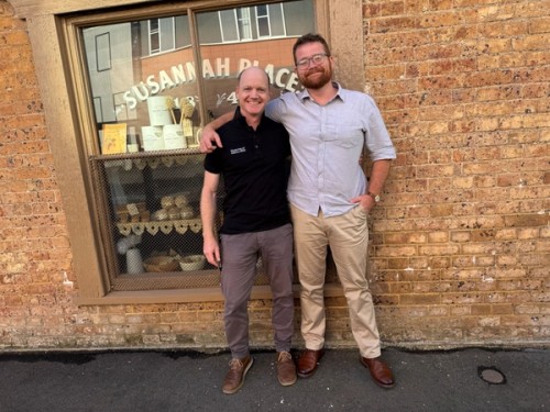Two men stand in front of the Susannah place shop window