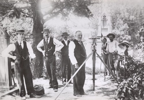 A group of men stand with their surveying equipment