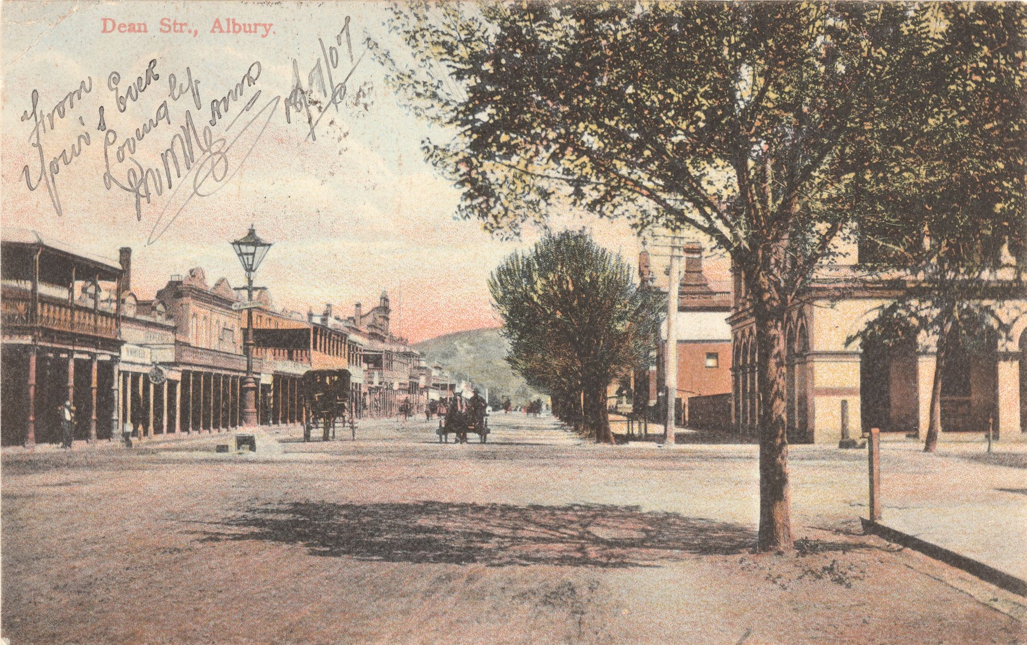 Postcard design with photo of street with buildings, trees, carts and horses 