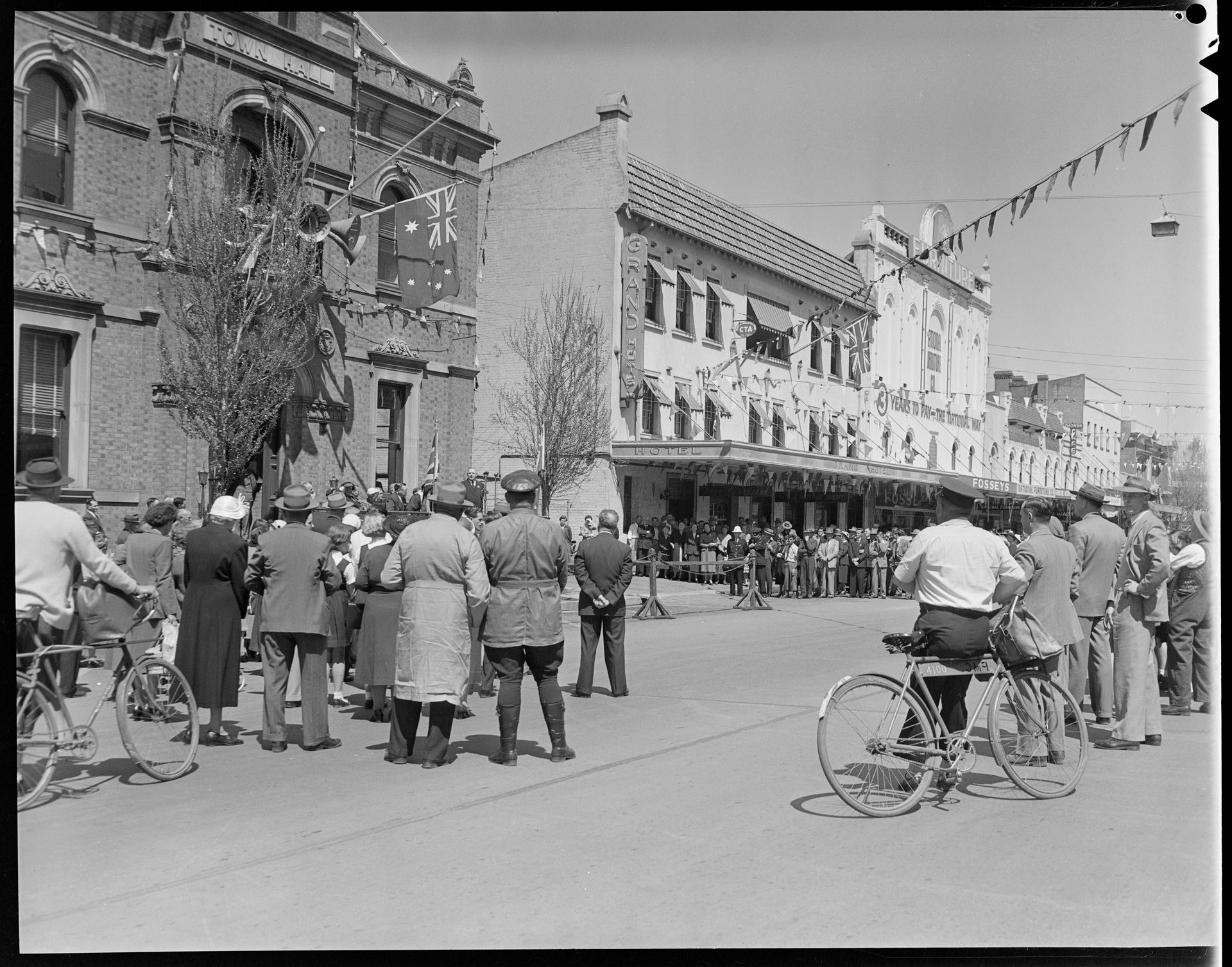 A view from the back of a crowd standing on the main street listening a speaker