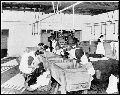 Black and white image of a group of women working at a wash tub