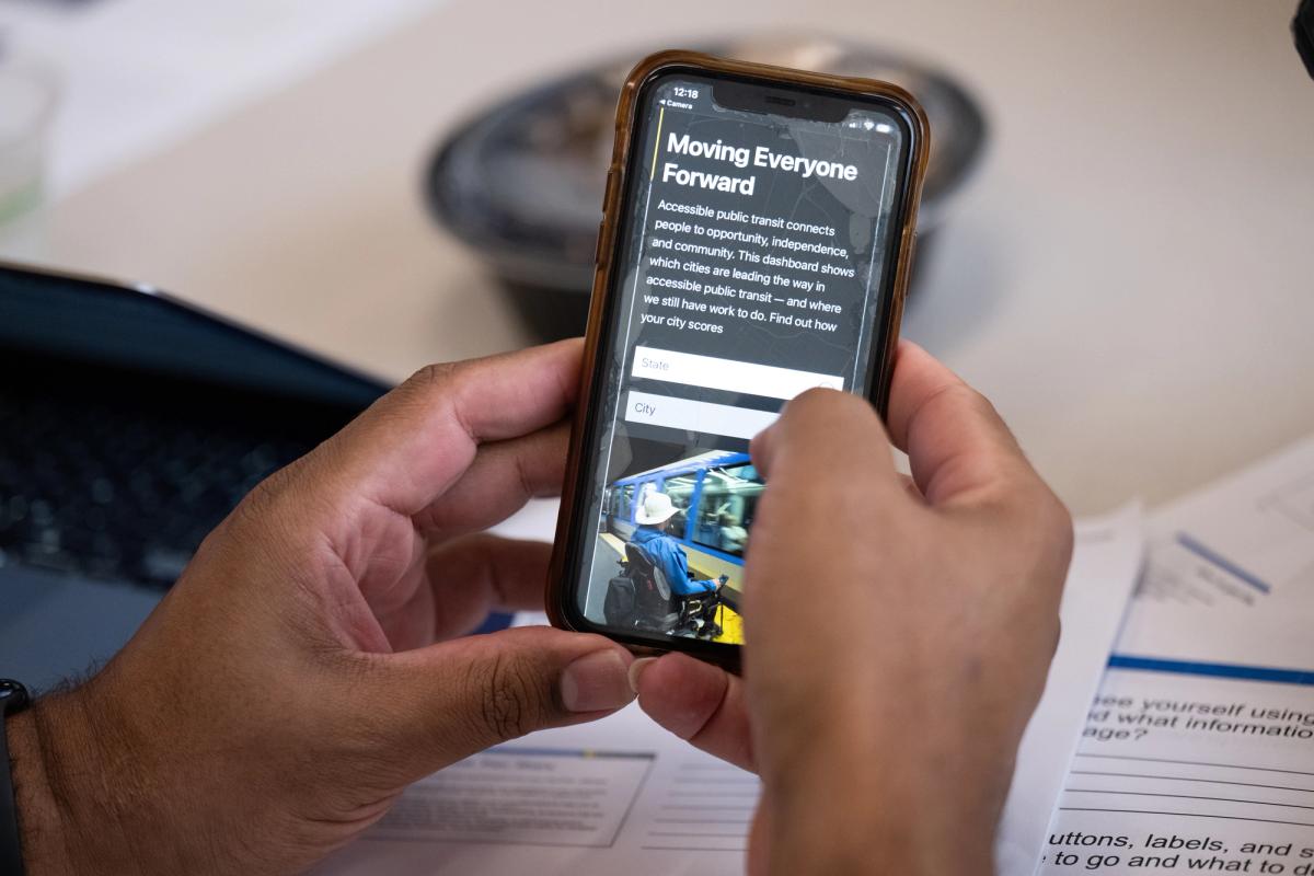 Hands holding a phone with a dashboard homepage displayed on it.