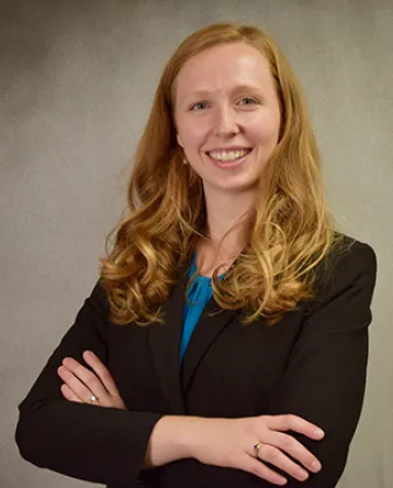 Erica Twardzik, with arms crossed, faces towards the camera