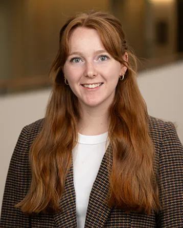 Christina Kiser, wearing a tweed blazer, faces the towards the camera