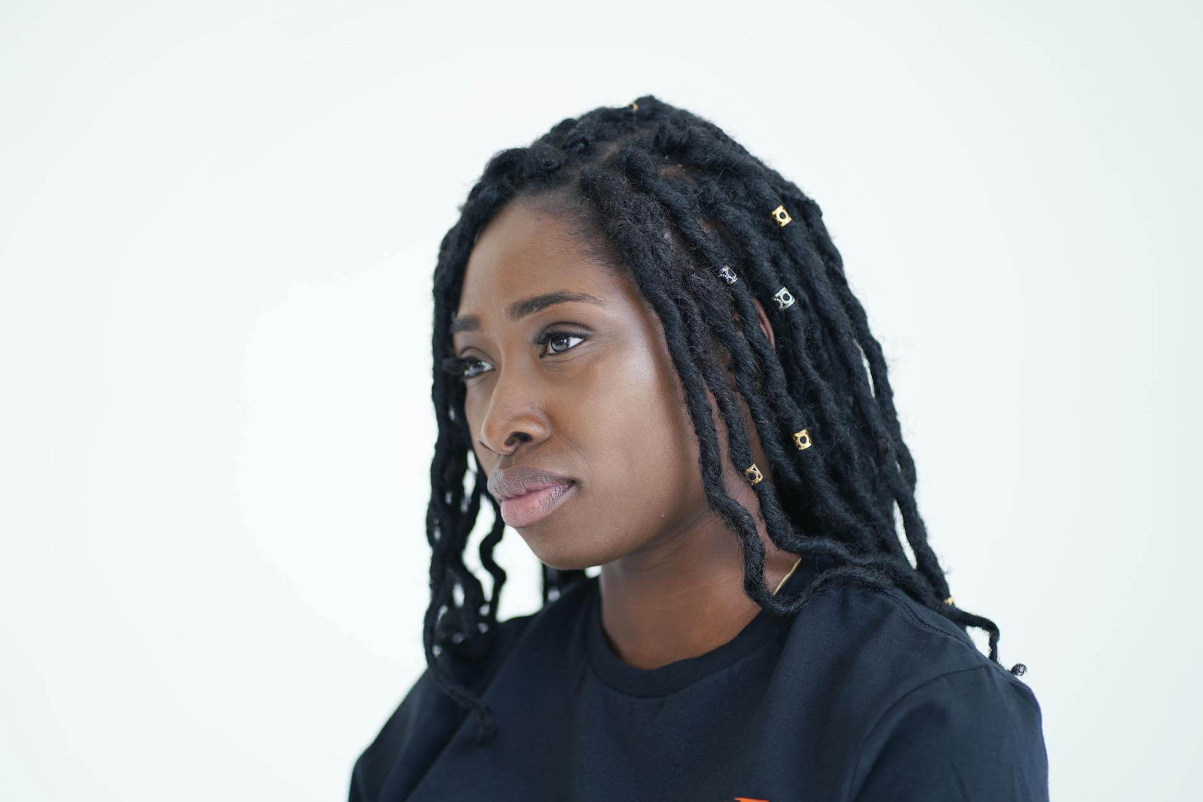 A stylish Black woman with textured hair elegantly wearing a colorful headwrap, showcasing various natural hair accessories, in a bright and well-lit setting.