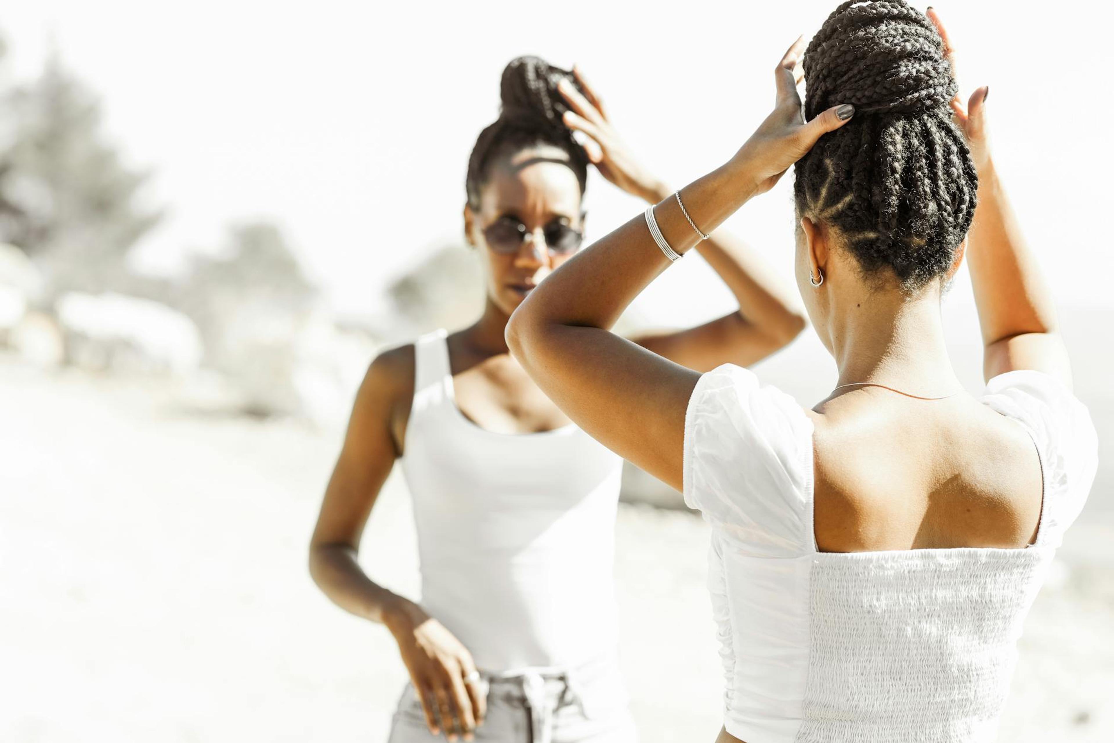 A close-up of a black woman with beautiful, textured hair styled in a protective hairstyle, smiling confidently in a well-lit environment, showcasing her natural beauty and healthy hair growth.