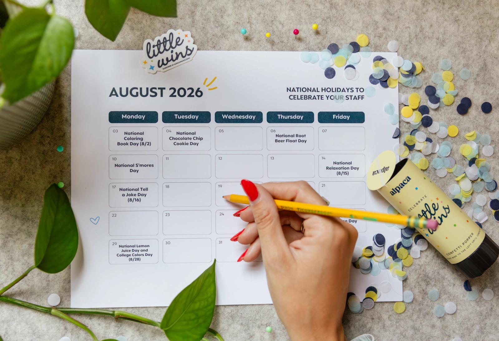 A hand writes on a paper with an August calendar on it. Confetti is scattered around the paper.