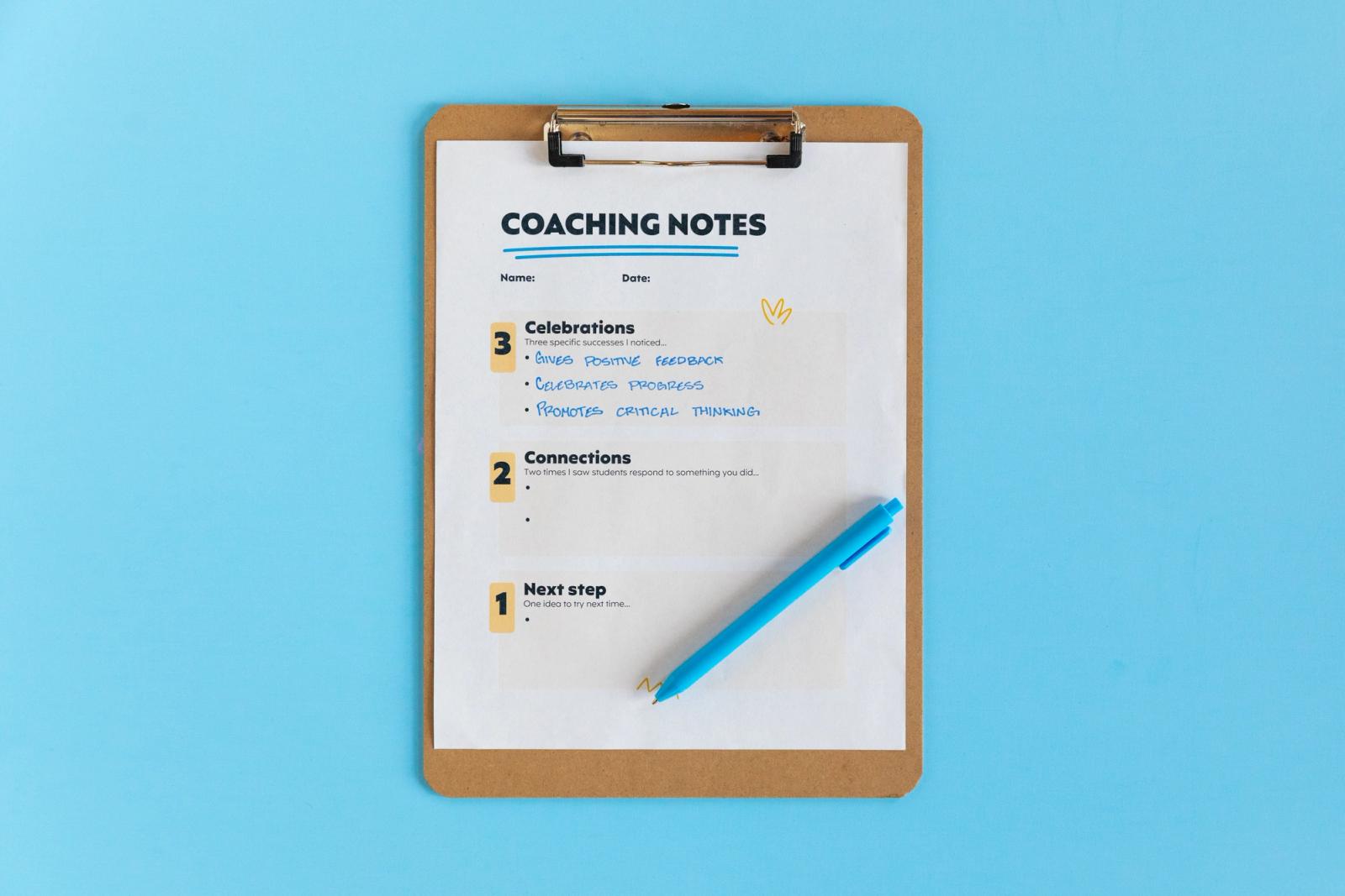 A clipboard with a sheet of paper and blue pen on it lay on a light blue background.