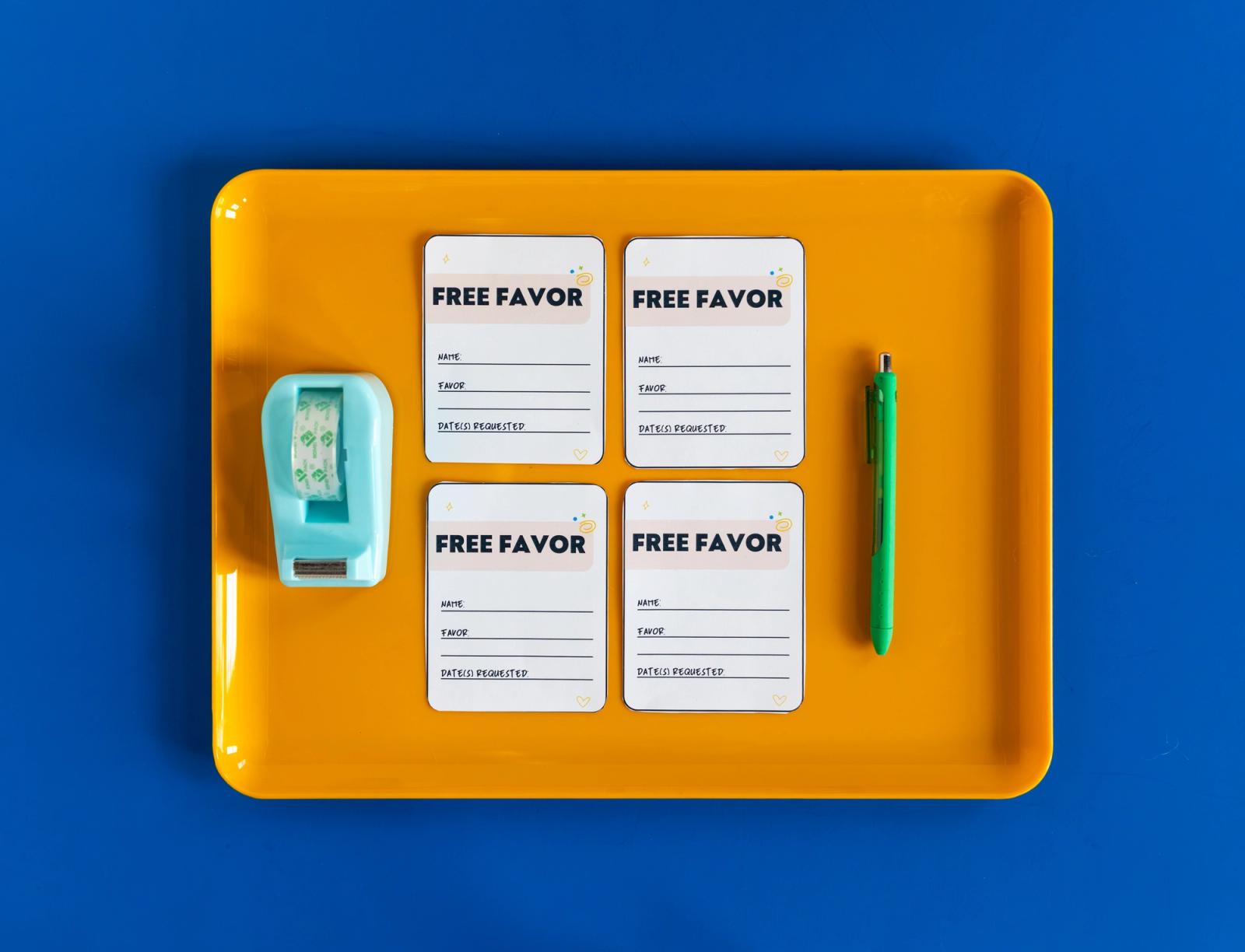 Four coupons that say "free favor" sit on an orange tray on a blue background. A tape dispenser and pen lay beside the coupons.