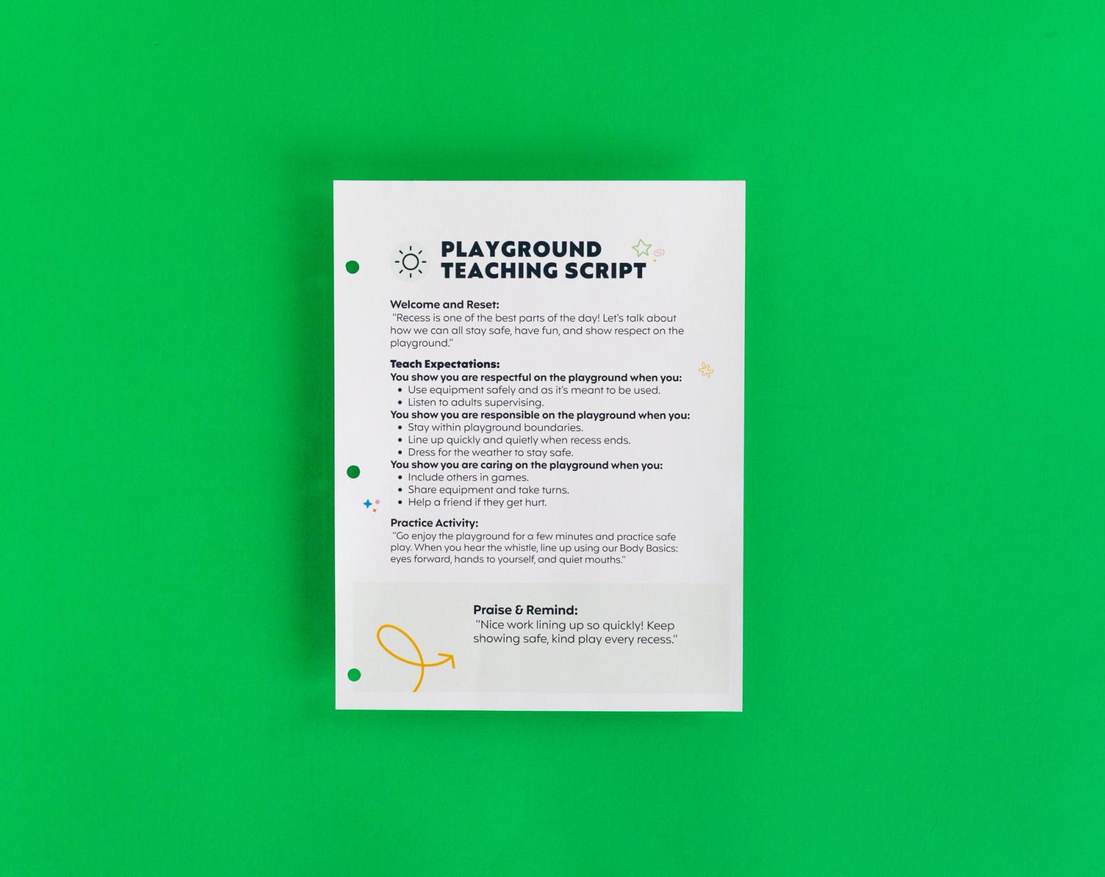 A sheet of paper that says "playground teaching script" on it lays on a green background.