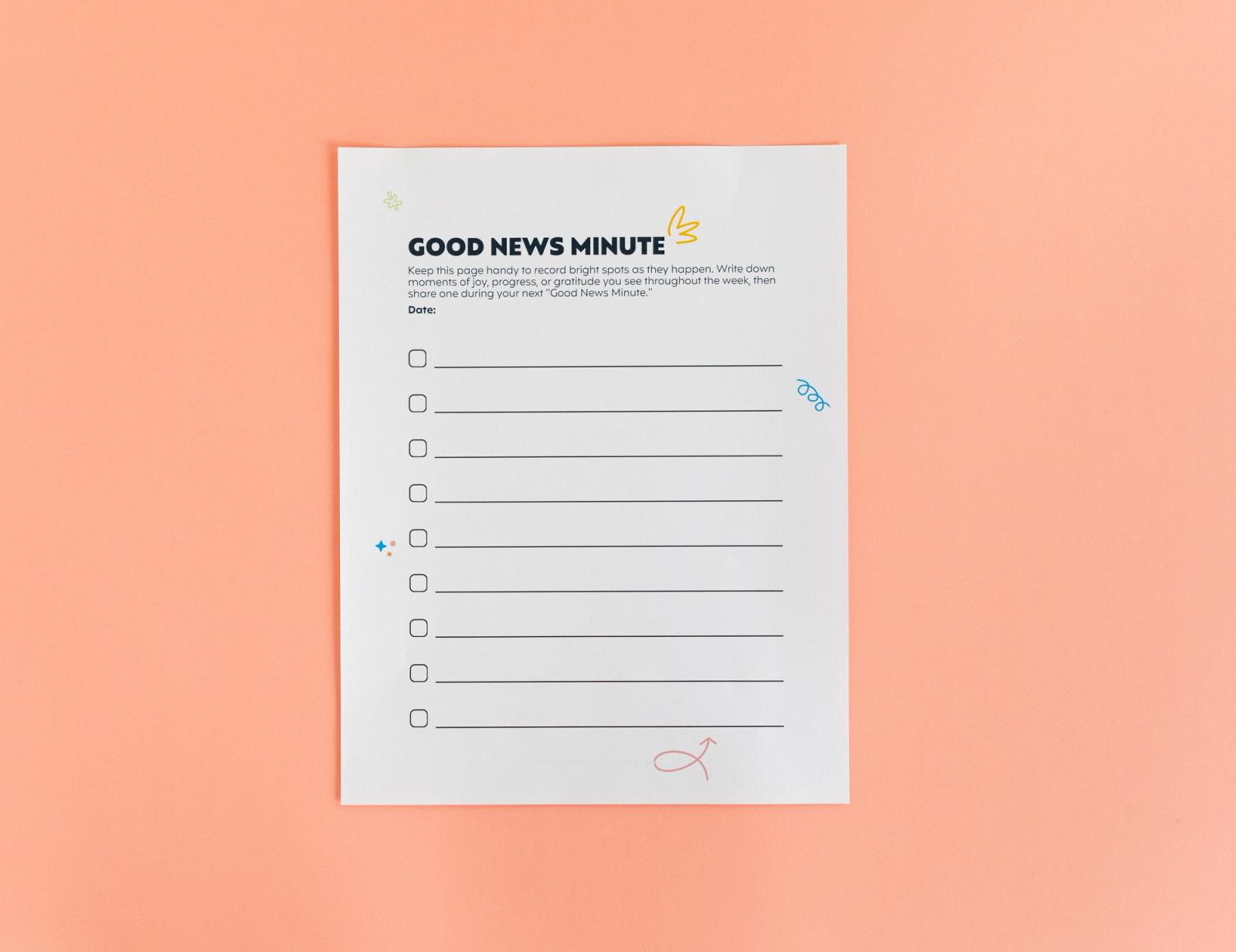 Sheet of paper that says "good news minute" lays on a salmon background.