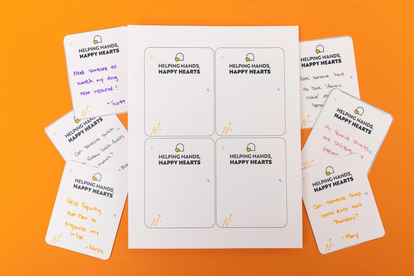 A piece of paper with four notecards that says "helping hands, happy hearts" and handwritten notes scattered around lays on an orange background.