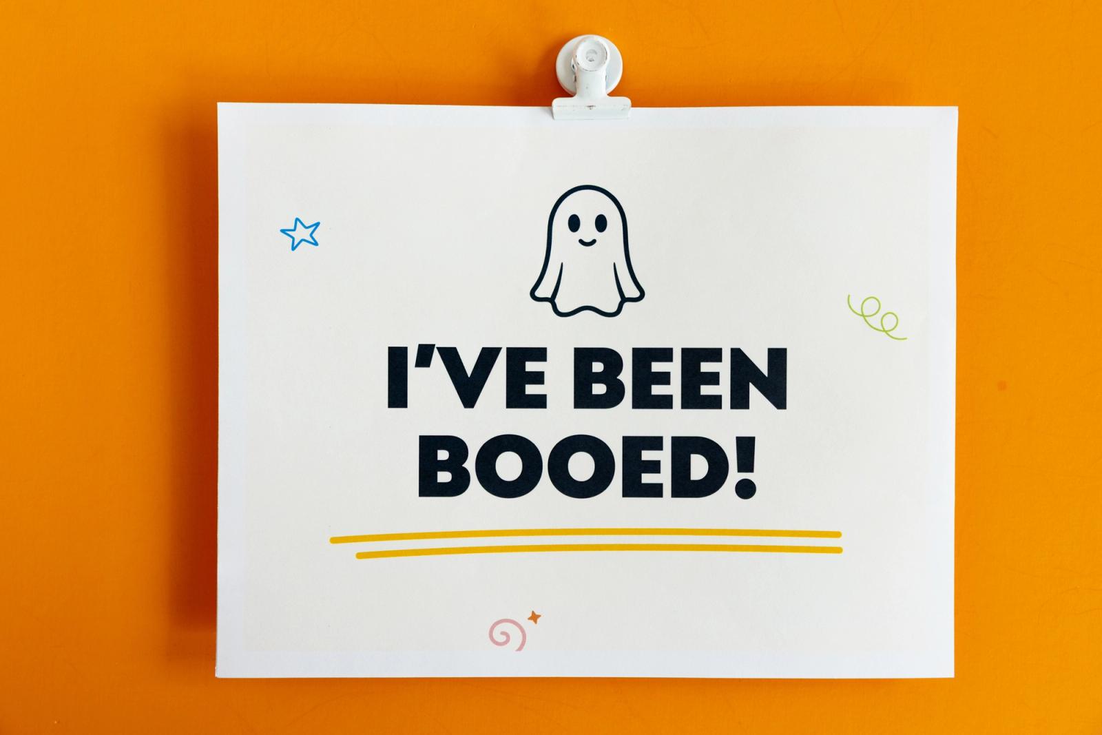 A piece of paper that says "I've been booed" lays on an orange background.