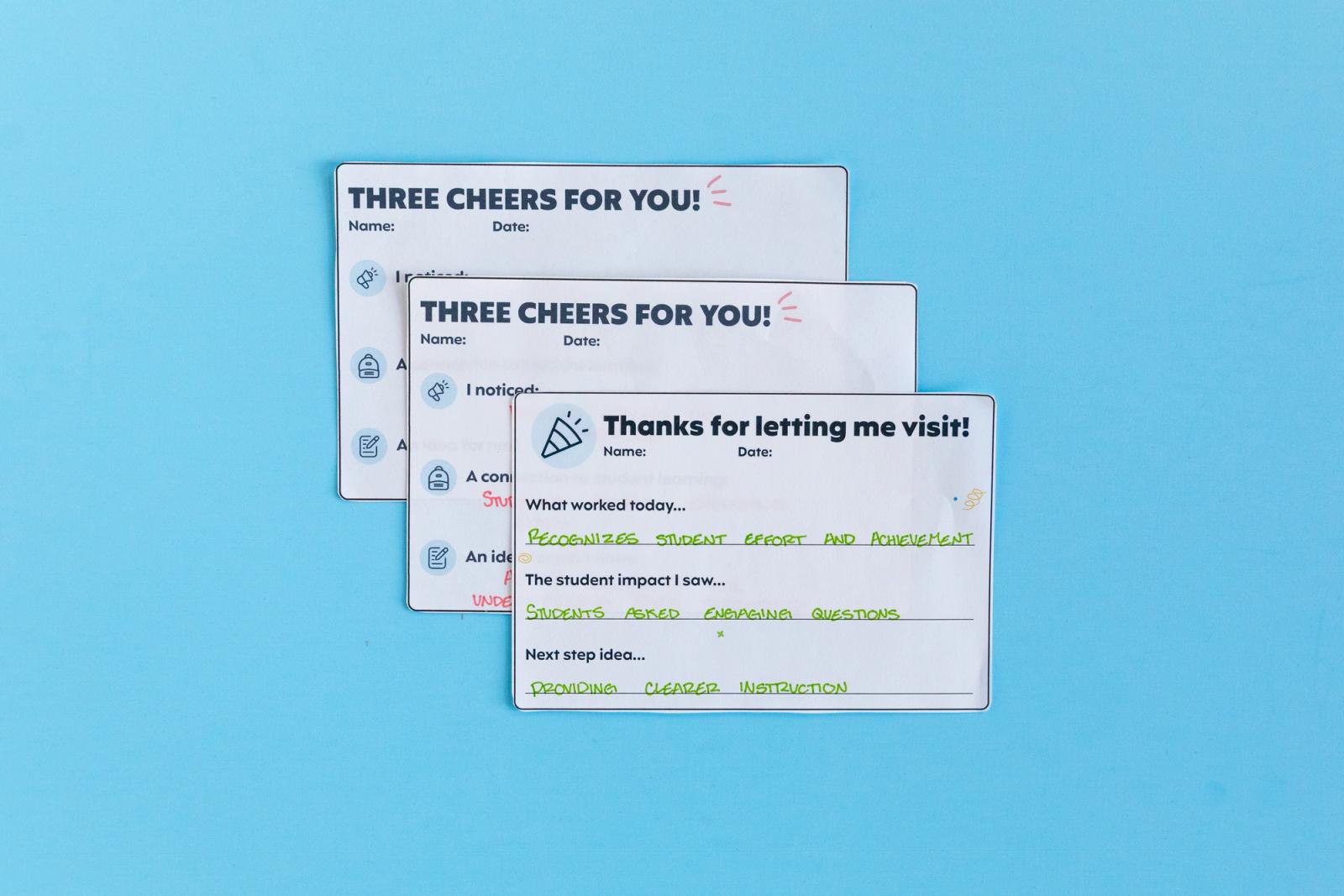 Three notecards with handwritten notes on them lay on a light blue background.