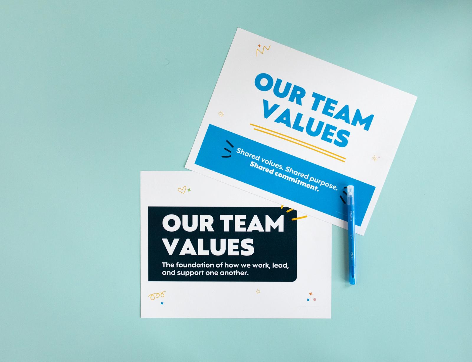 Two posters with "our team values" printed on them lay on a light blue background.