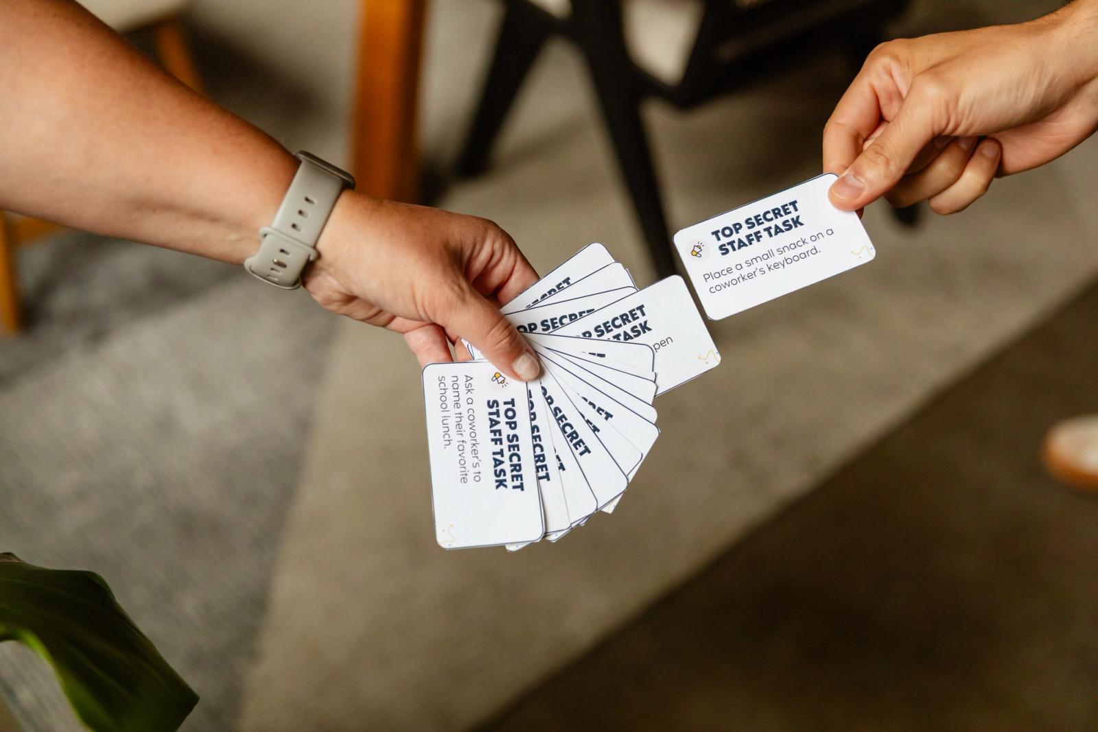 A hand reaches in to pull out a card from a stack someone else is holding.