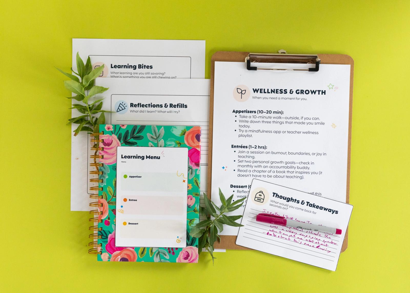 A large clipboard with a piece of paper on it lays on a light green background. Next to it are more papers and a notecard that says "learning menu" on it. Green leaves are scattered around.