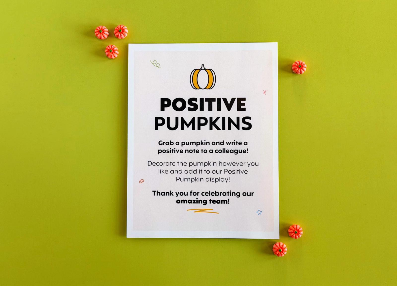 Positive Pumpkins directions sign inviting staff to write a positive note to a colleague on a paper pumpkin, with mini pumpkins on a green background.