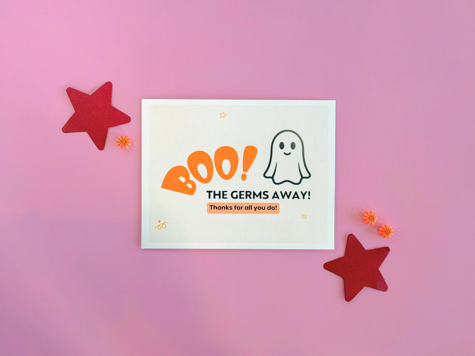 “Boo the germs away” Halloween treat station sign with a smiling ghost, red paper stars, and pumpkin candies