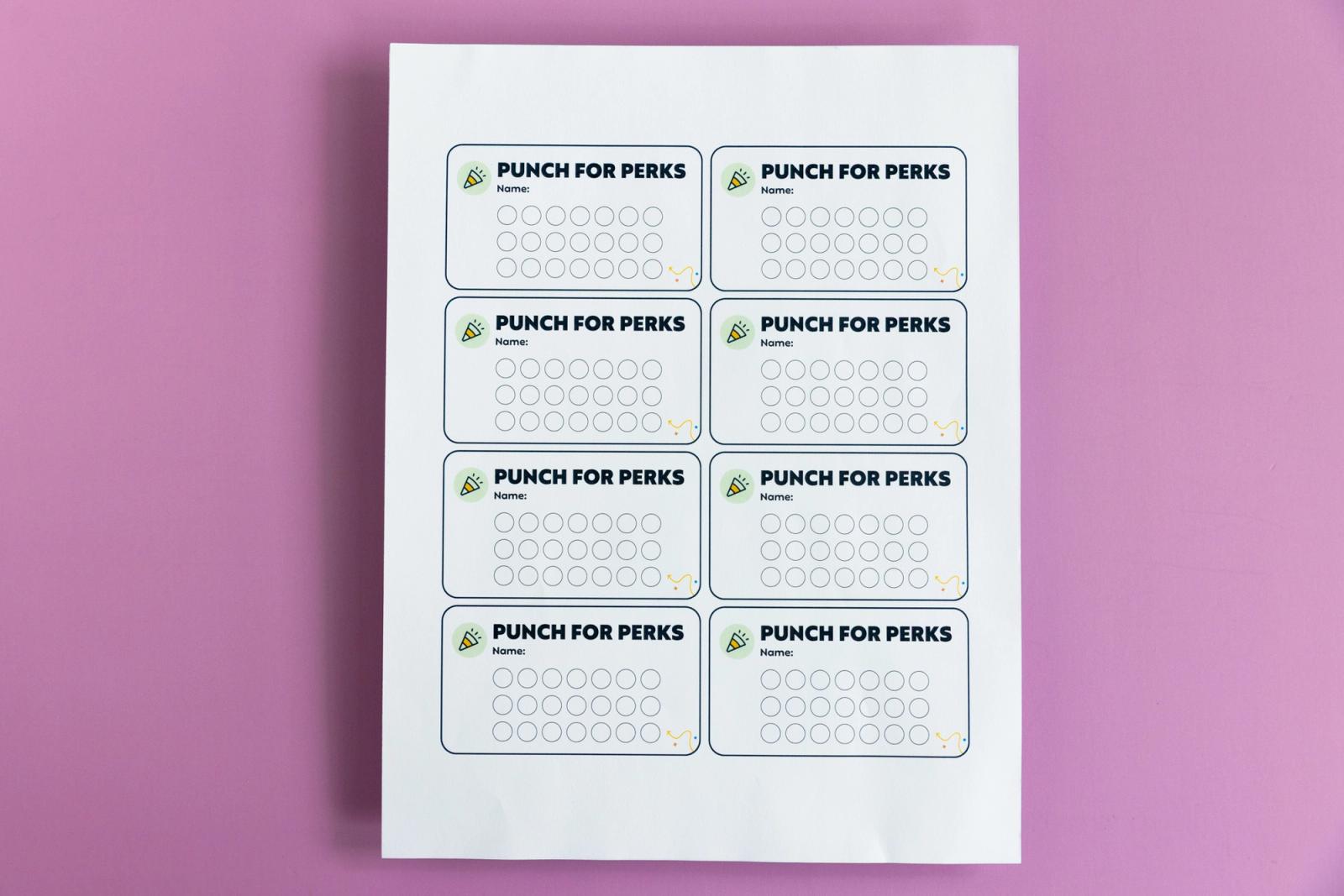 A sheet of paper with eight notecards on it that say "punch for perks" lays on a light purple background.