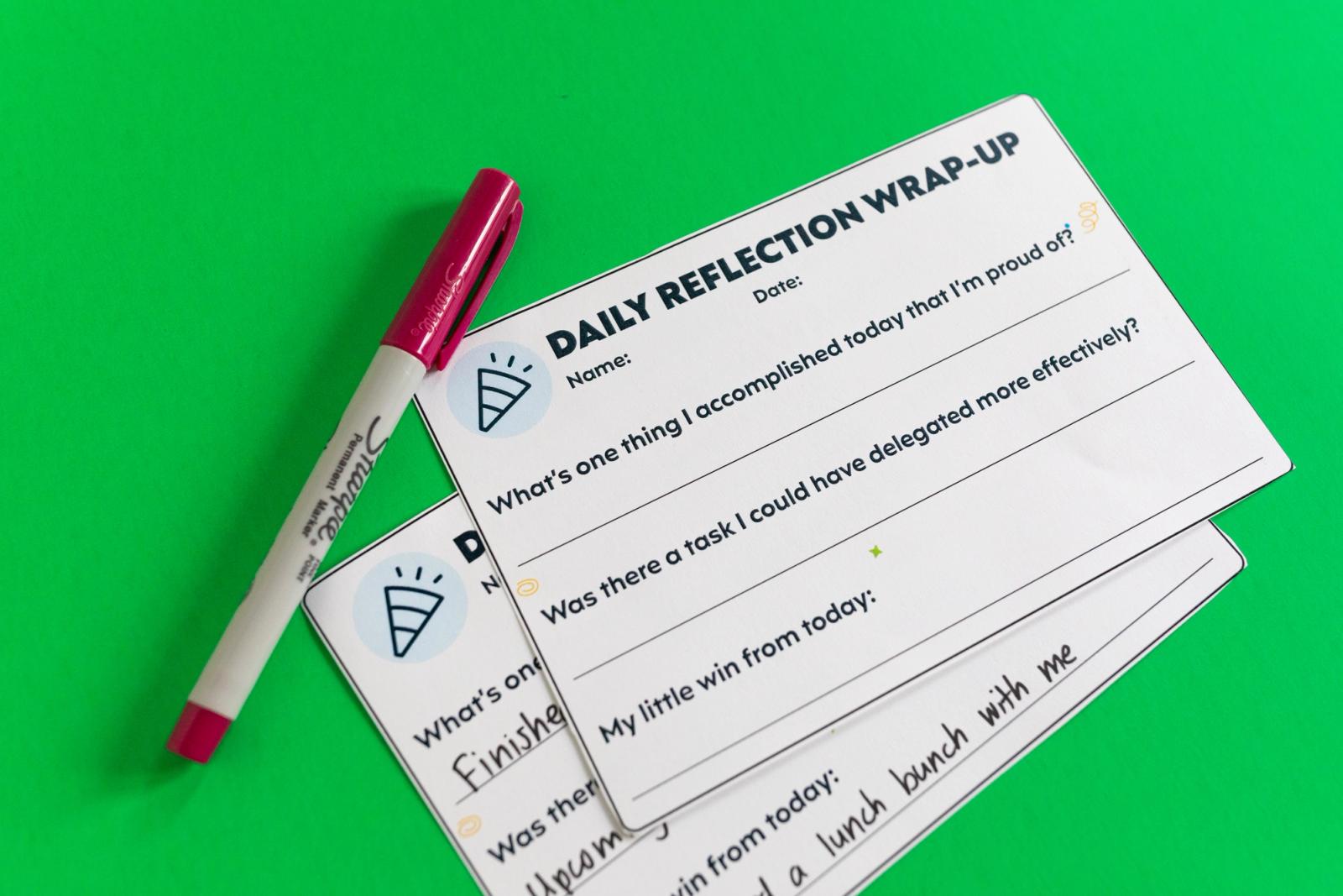 Two notecards and a red pen lay on a green background.