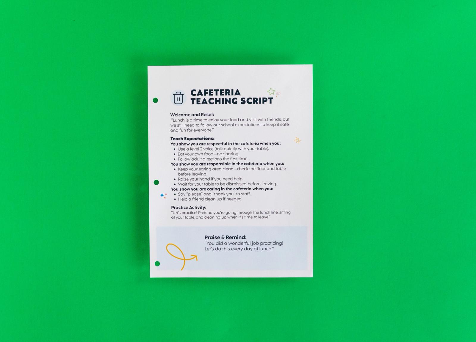 A sheet of paper that says "cafeteria teaching script" on it lays on a green background.