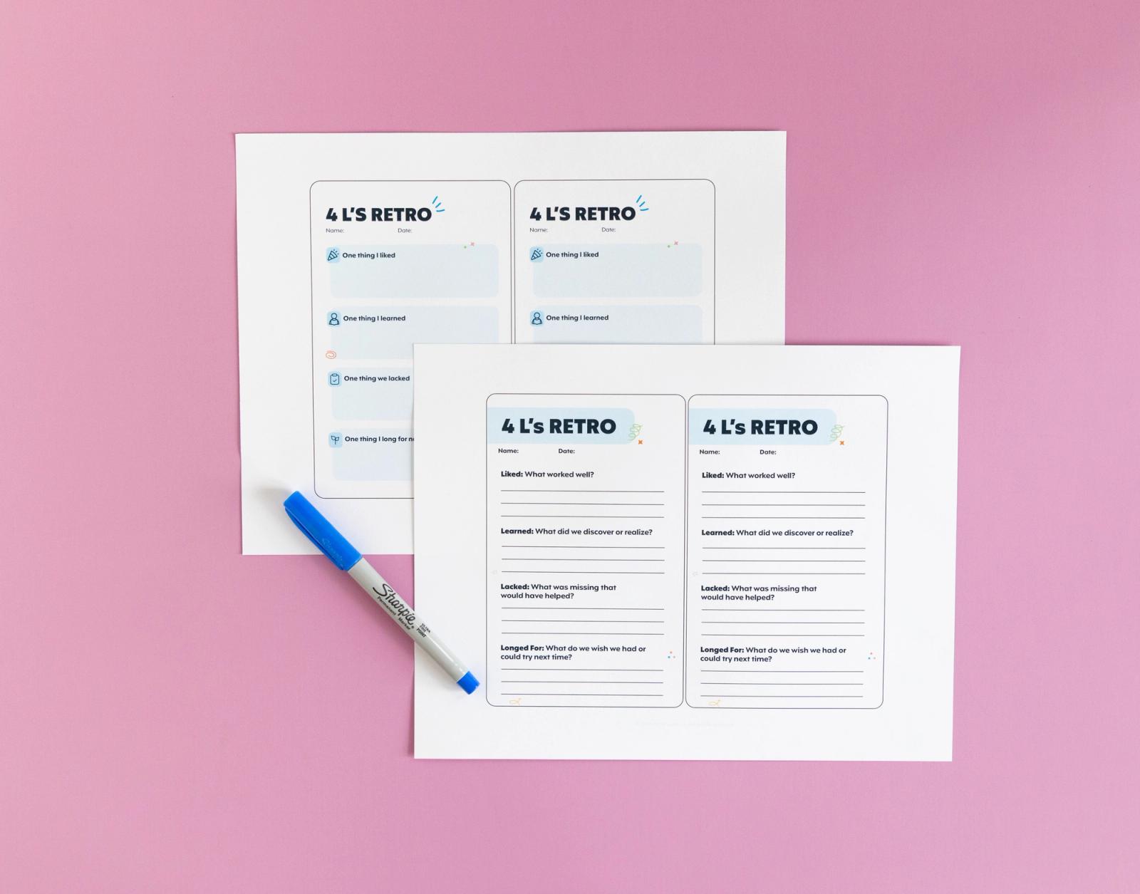 Two sheets of paper with notecards on them lay on a pink background. A blue pen lays next to them.