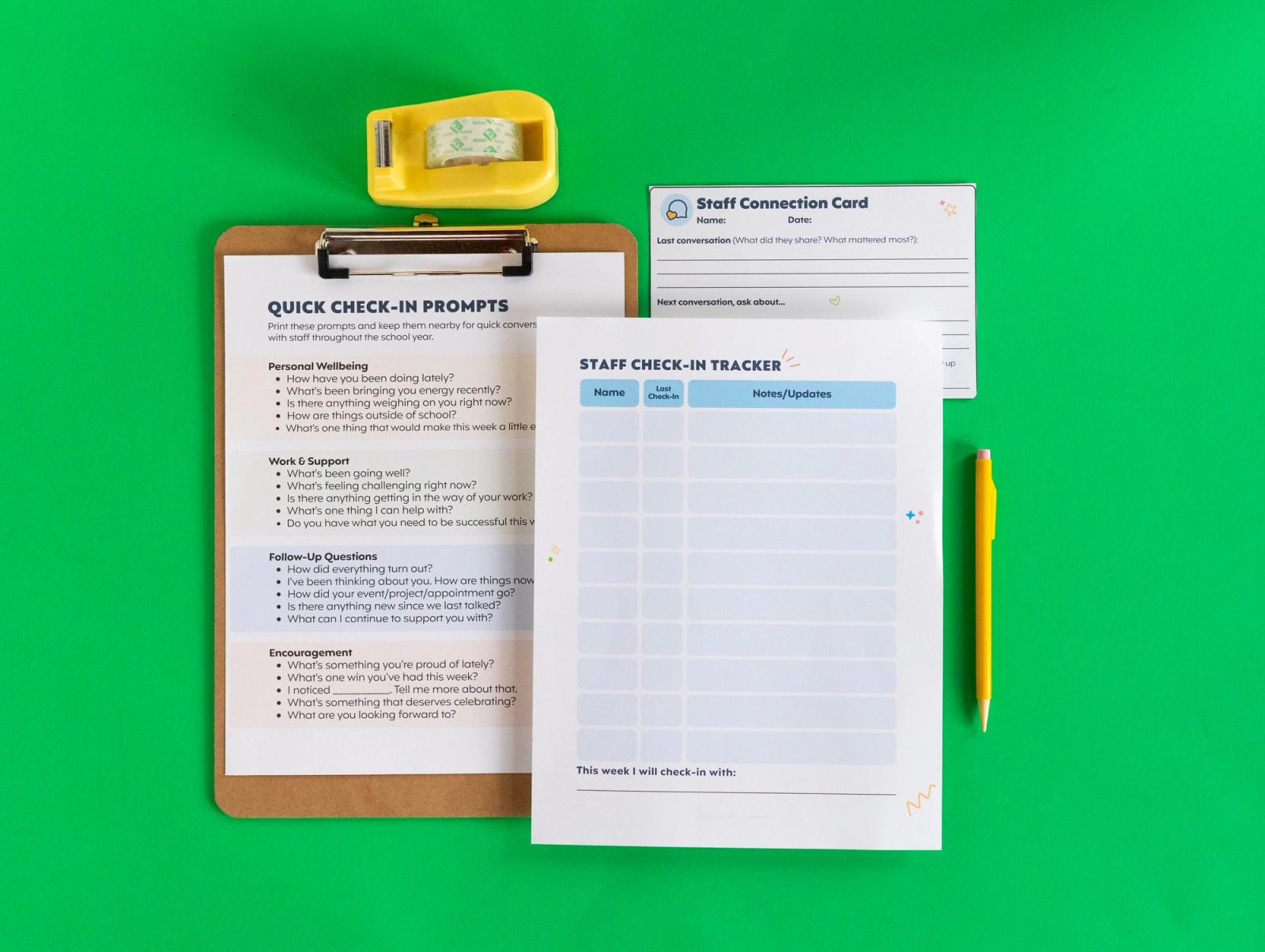 Several sheets of paper a clipboard, tape dispenser, and pencil lay on a green bac