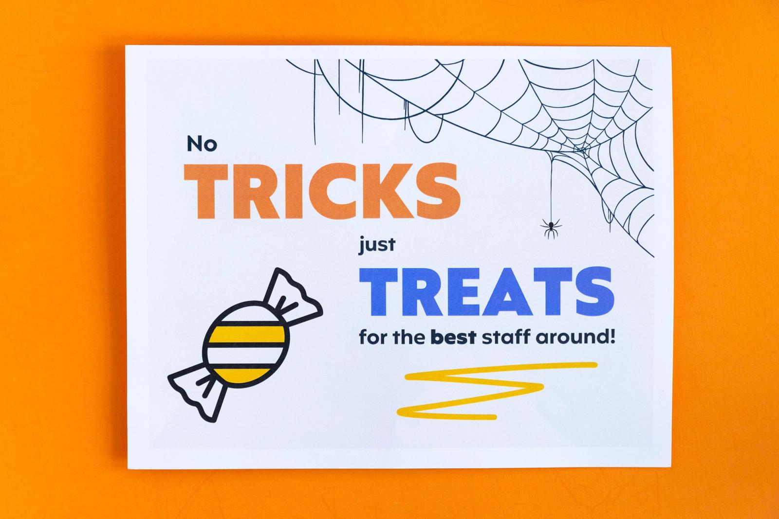 A paper that says "no tricks just treats" lays on an orange background.