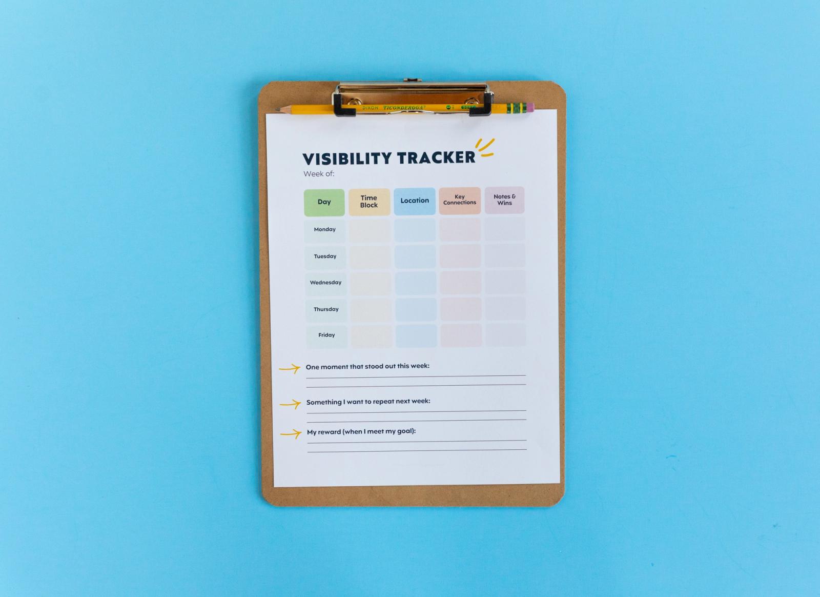 A piece of paper that says "visibility tracker" on a clipboard lays on a light blue background.