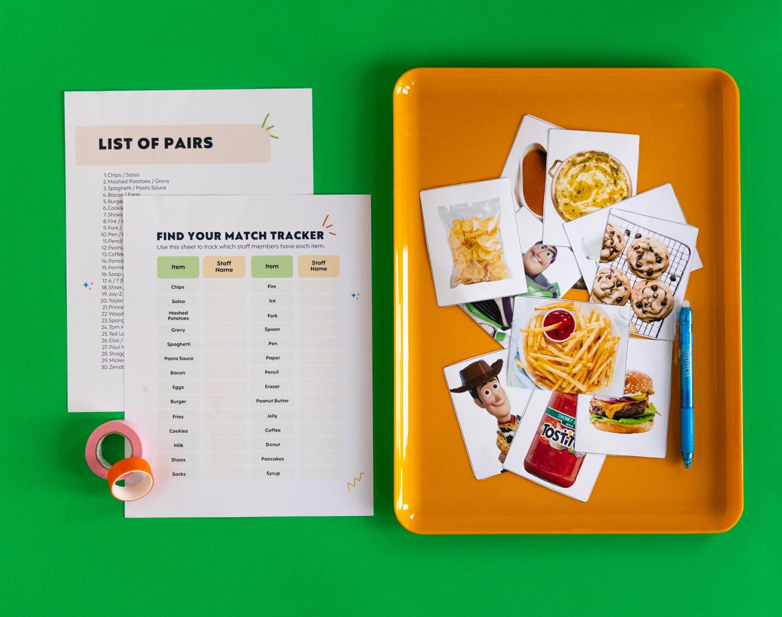 Two sheets of paper and orange tape lay on a green background. Beside them is an orange tray with cutout prints of images on it.