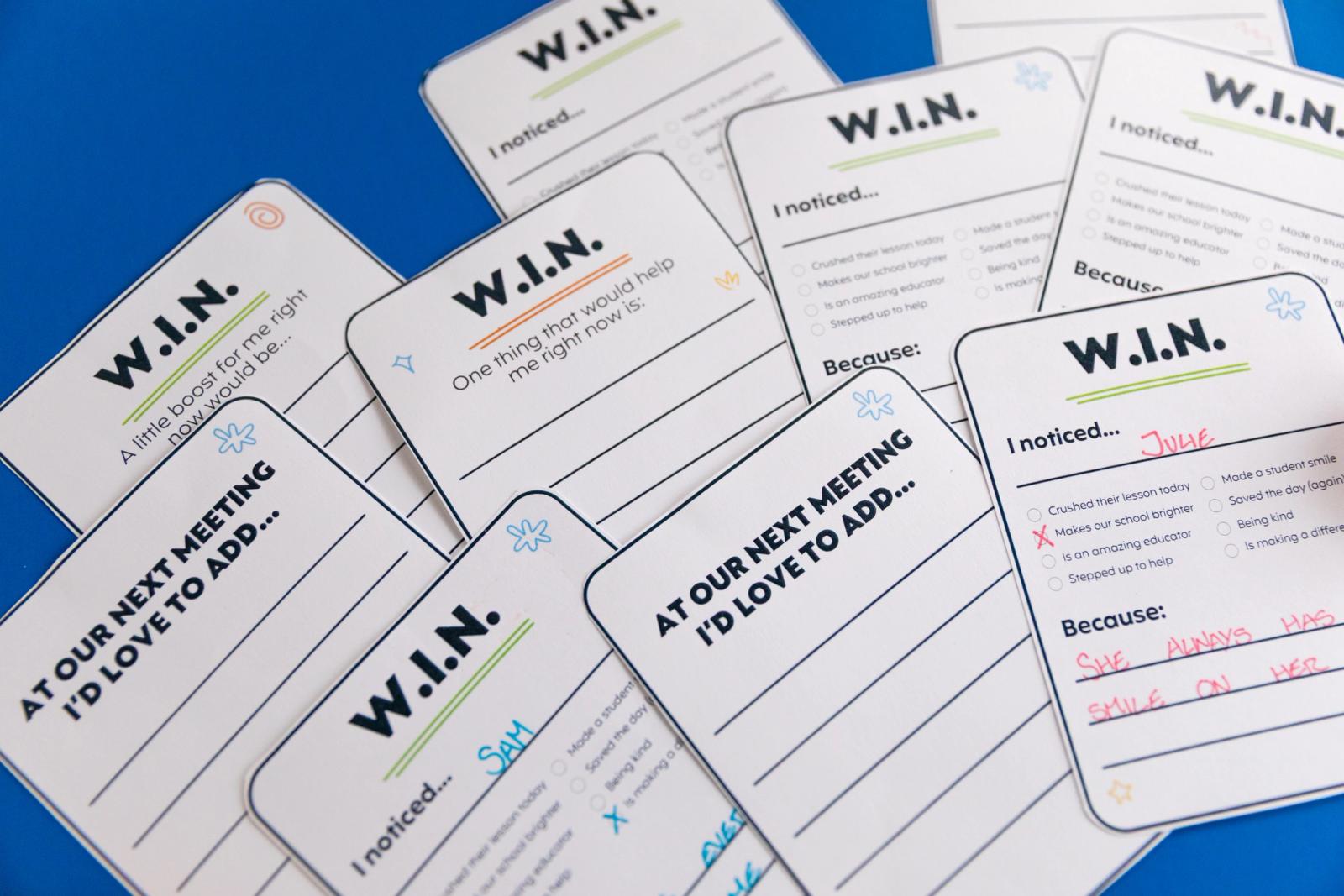 Closeup of notecards that say "w.i.n." on them on a dark blue background.