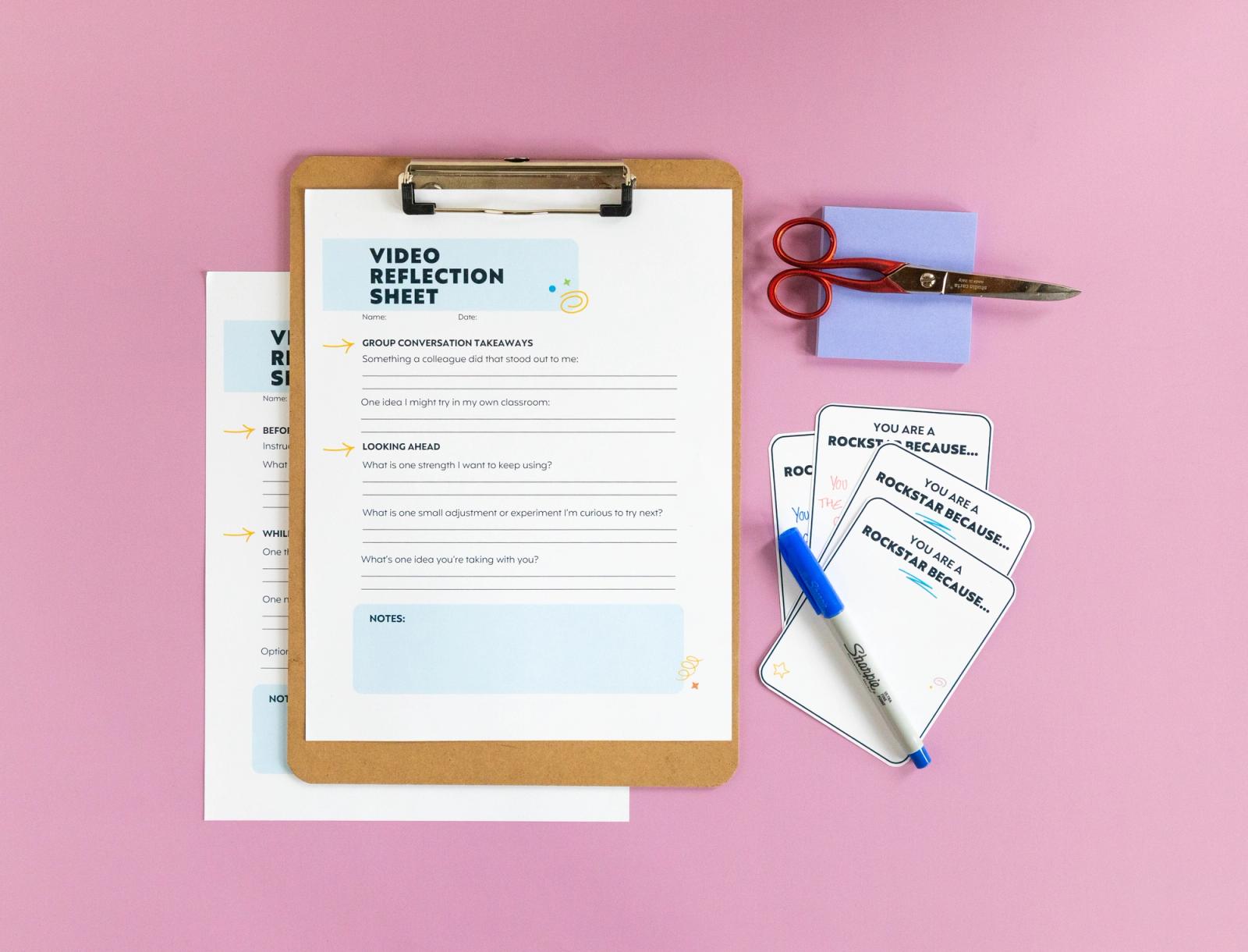 Sheet of paper, clipboard with a sheet of paper, notecards, marker, scissors and sticky-notes lay on a pink background.