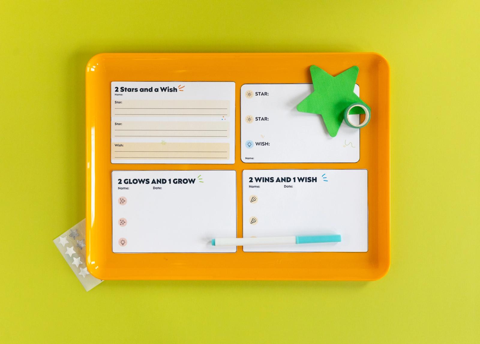 Four notecards and a green star lay on an orange tray on a lime green background.